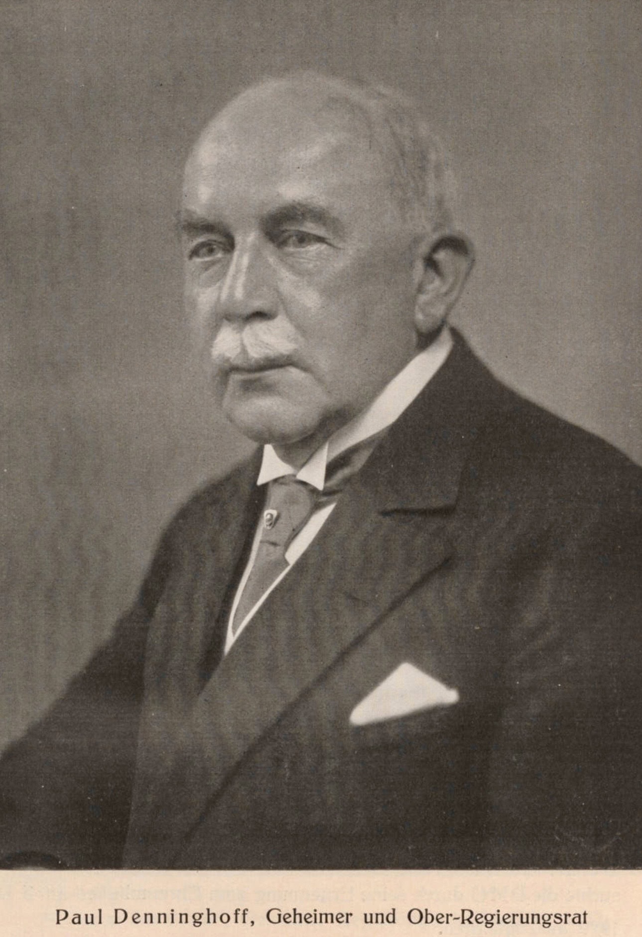 Paul Denninghoff um 1930 Ein schwarz-weiß Foto von einem älteren Herren im Anzug mit Schnauzbart und Glatze: Paul Denninghoff.