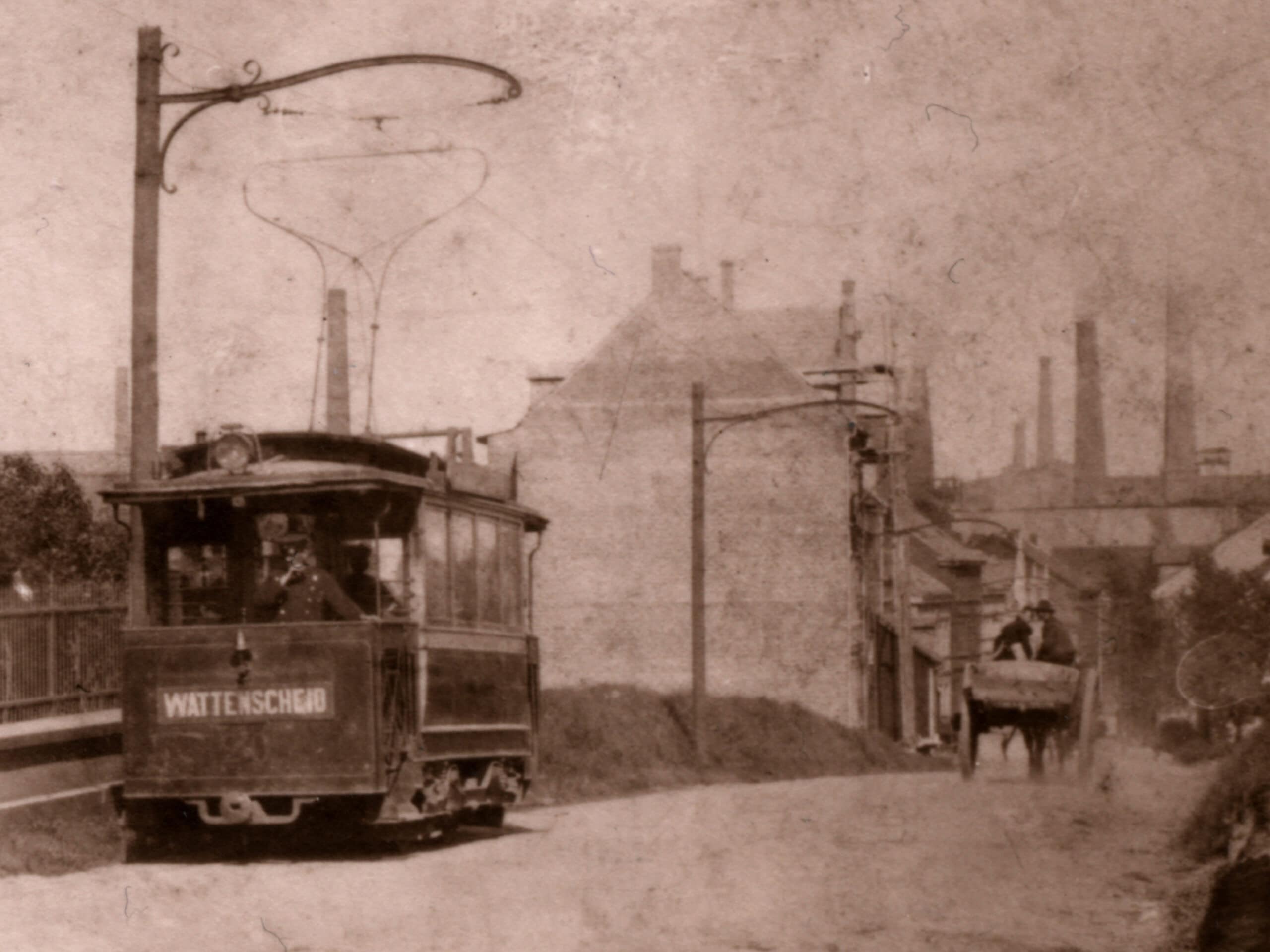 Hamme Bahn und Stahlwerk Ein historischer Straßenbahnwagen fährt durch das historische Bochum Hamme vorbei am Stahlwerk. Ein Pferdewagen fährt auf der anderen Spur.