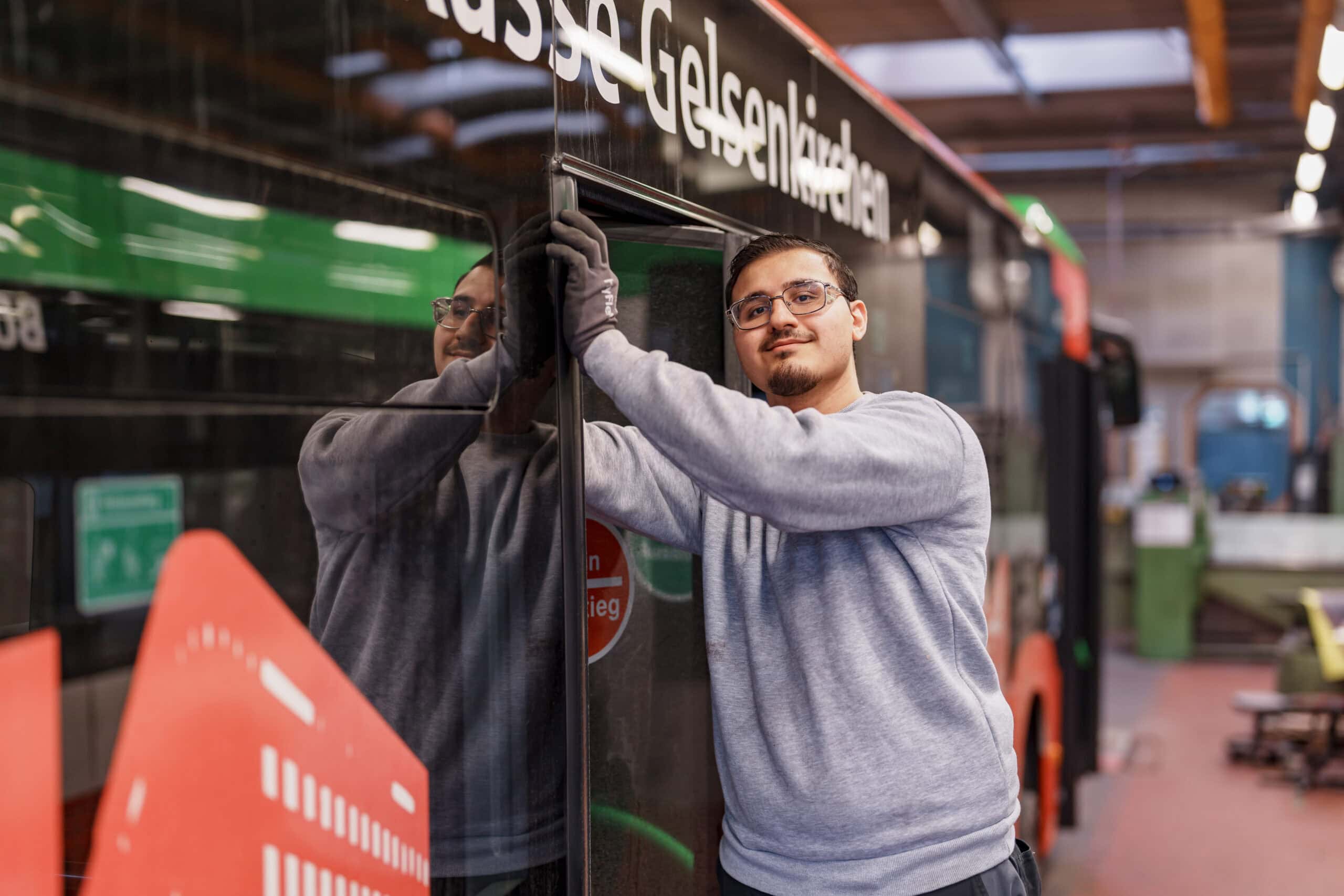Unser Kollege Muthanna steht halb in der hinteren Tür eines Busses und arbeitet am Türgummi.
