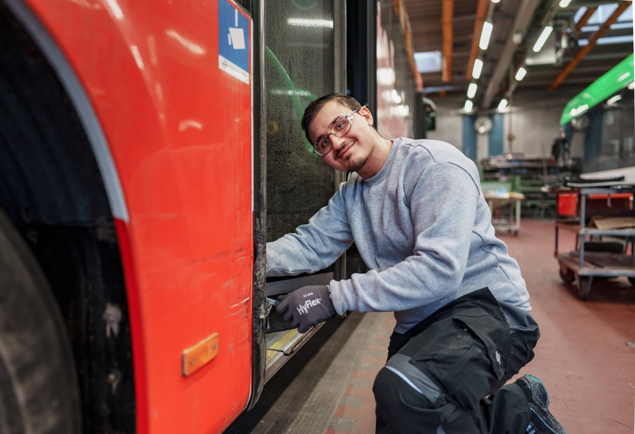 Unser Kollege Muthanna kniet vor der hinteren Bustür und arbeitet am Türgummi.