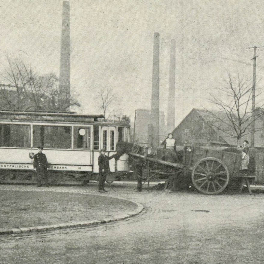 Historisches Bild mit Frauen auf einem Wagen hinter einer Straßenbahn.