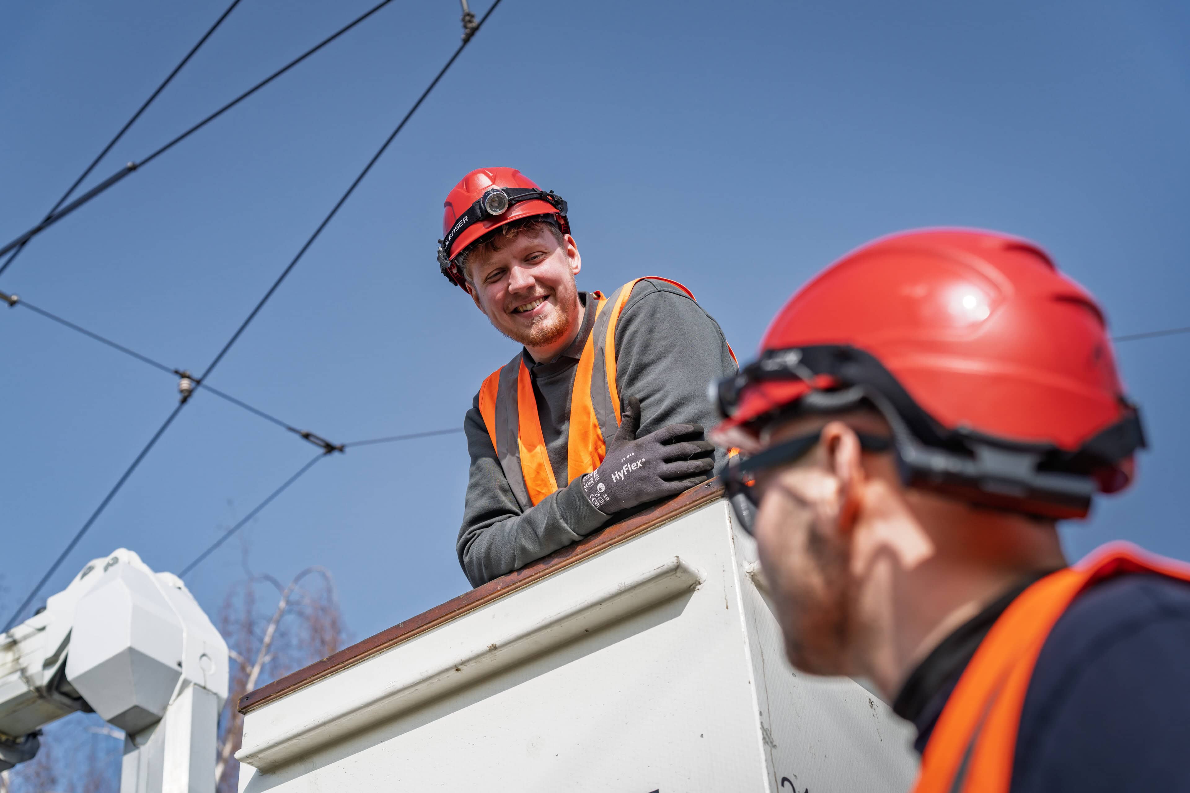 Ein Mann in Warnkleidung guckt lachend aus dem Arbeitskorb eines Hubarbeitswagens.